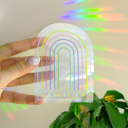 Bunte Suncatcher-Sticker in Regenbogenfarben, auf einem sonnendurchfluteten Fenster angebracht. Die Sticker reflektieren das Licht und erzeugen leuchtende Farben, ideal für Kinderzimmer oder kreative Dekoration