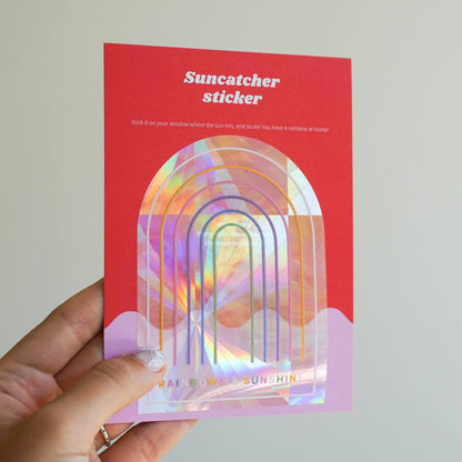 Sonnenfänger-Sticker von Laufkleber, präsentiert mit ihrer Verpackung. Die Sticker schimmern in Regenbogenfarben und sind ideal für Fensterdekoration oder kreative Bastelideen.